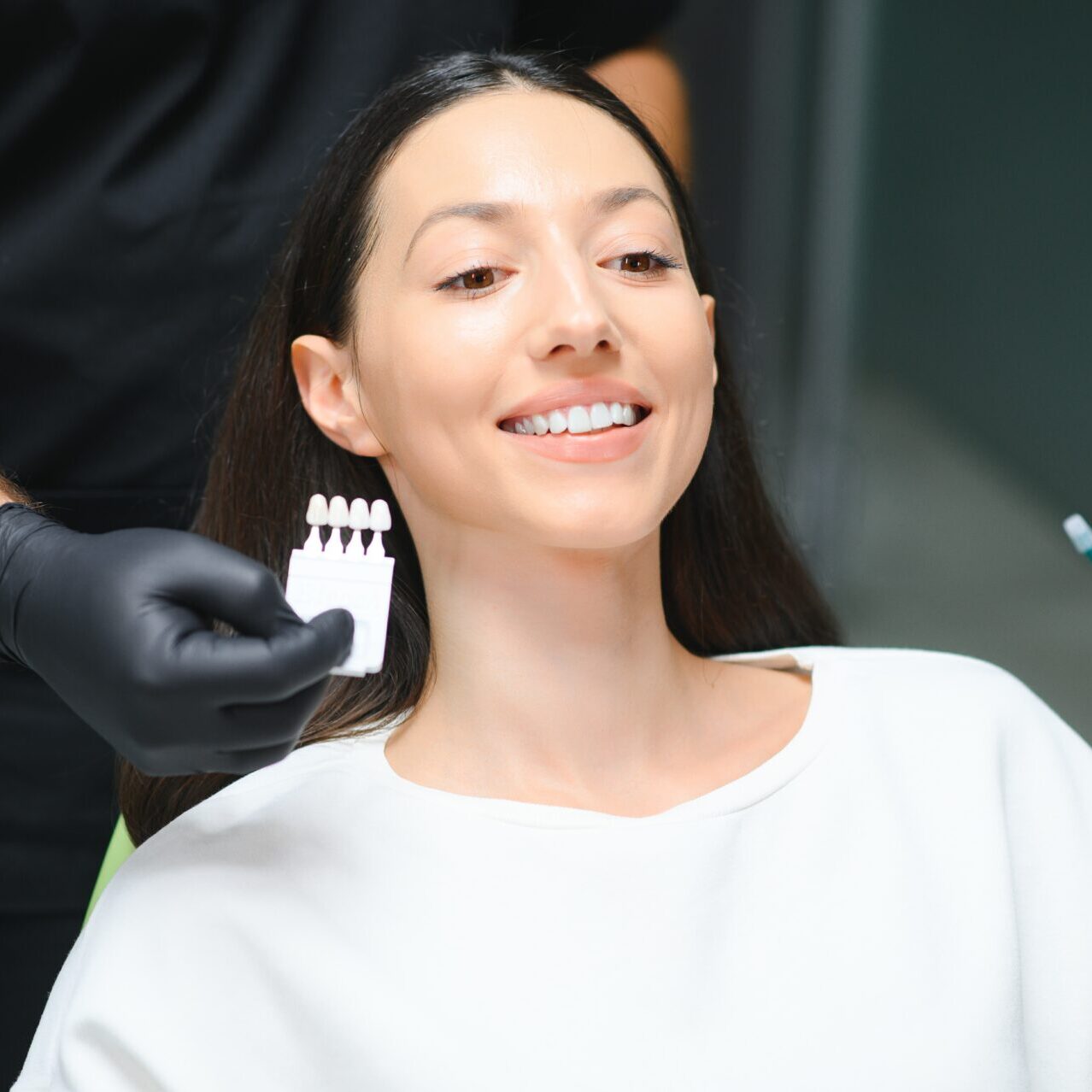 Teeth whitening in Toorak - Toorak dentist checking and selecting color of young woman's teeth.