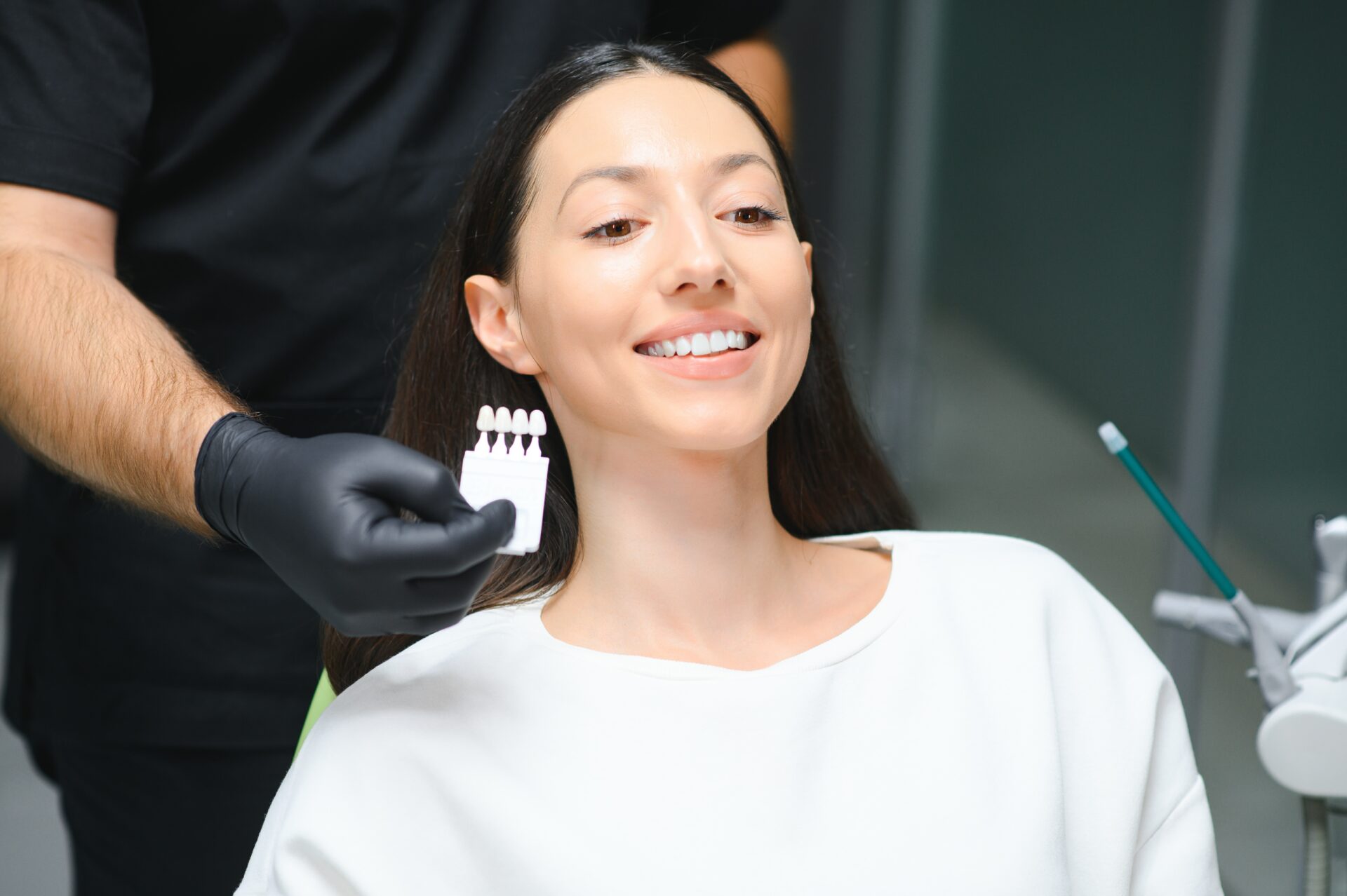 Teeth whitening in Toorak - Toorak dentist checking and selecting color of young woman's teeth.